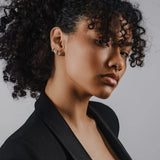 Model wearing the Mini Clear Huggies, a pair of small silver hoop earrings with sparkling clear cubic zirconia stones.||| SILVER