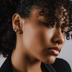 Model wearing the Mini Clear Huggies, a pair of small silver hoop earrings with sparkling clear cubic zirconia stones.||| SILVER