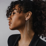 Model wearing three Tennis Earring Chains, a single long silver chain earring with tiny sparkling stones.||| SILVER