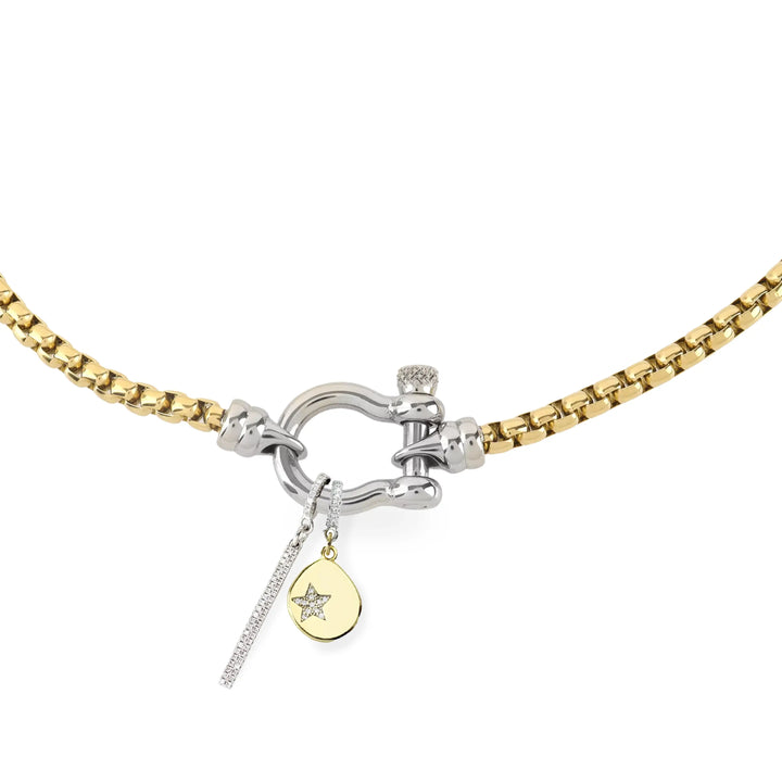 The HERRADURA SIGNATURE DOUBLE TAKE featuring a gold chain with a silver horseshoe clasp and dangling charms, including a pavé bar and a gold star pendant. ||| SILVER
