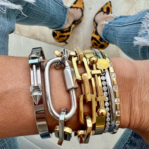  woman wearing ripped jeans and leopard print pumps stacks a variety of bold artizan gold and silver bracelets on her left wrist