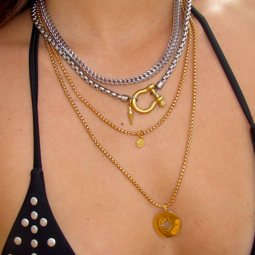 Close-up of a bold jewelry look featuring Artizan Joyeria’s Herradura Layered Necklace set against a black swimsuit.