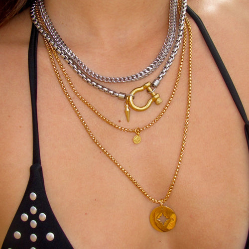 Close-up of a bold jewelry look featuring Artizan Joyeria’s Herradura Layered Necklace set against a black swimsuit.