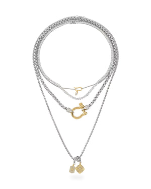 Layered silver necklaces with gold accents featuring a gold clasp pendant and two small gold charm pendants on the longest chain