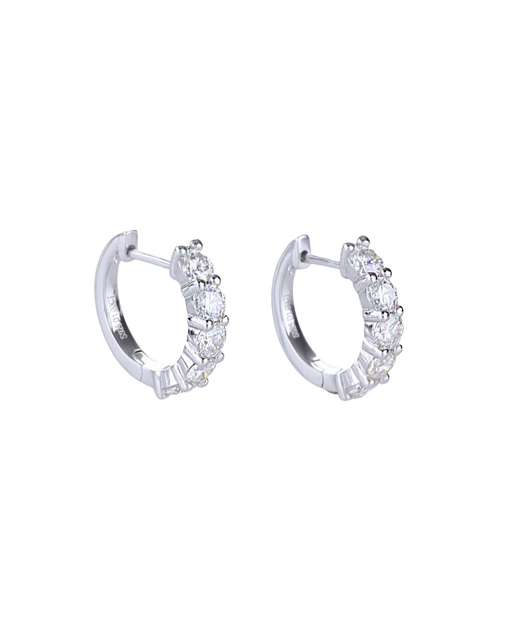 The Main Hoop, which is a pair of silver-tone hoop earrings featuring a row of dazzling round-cut stones along the front, offering a statement design that combines elegance and brilliance for any occasion.