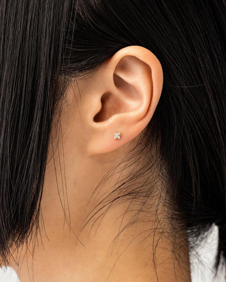 Small, four-petal flower stud earring featuring round cubic zirconia stones set in a gold base