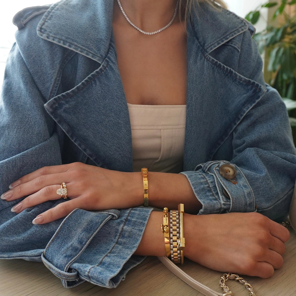 a woman wearing a jean jacket and a white strapless top, she is with her arms crossed, wearing mix metal bracelets all of them from artizan joyeria