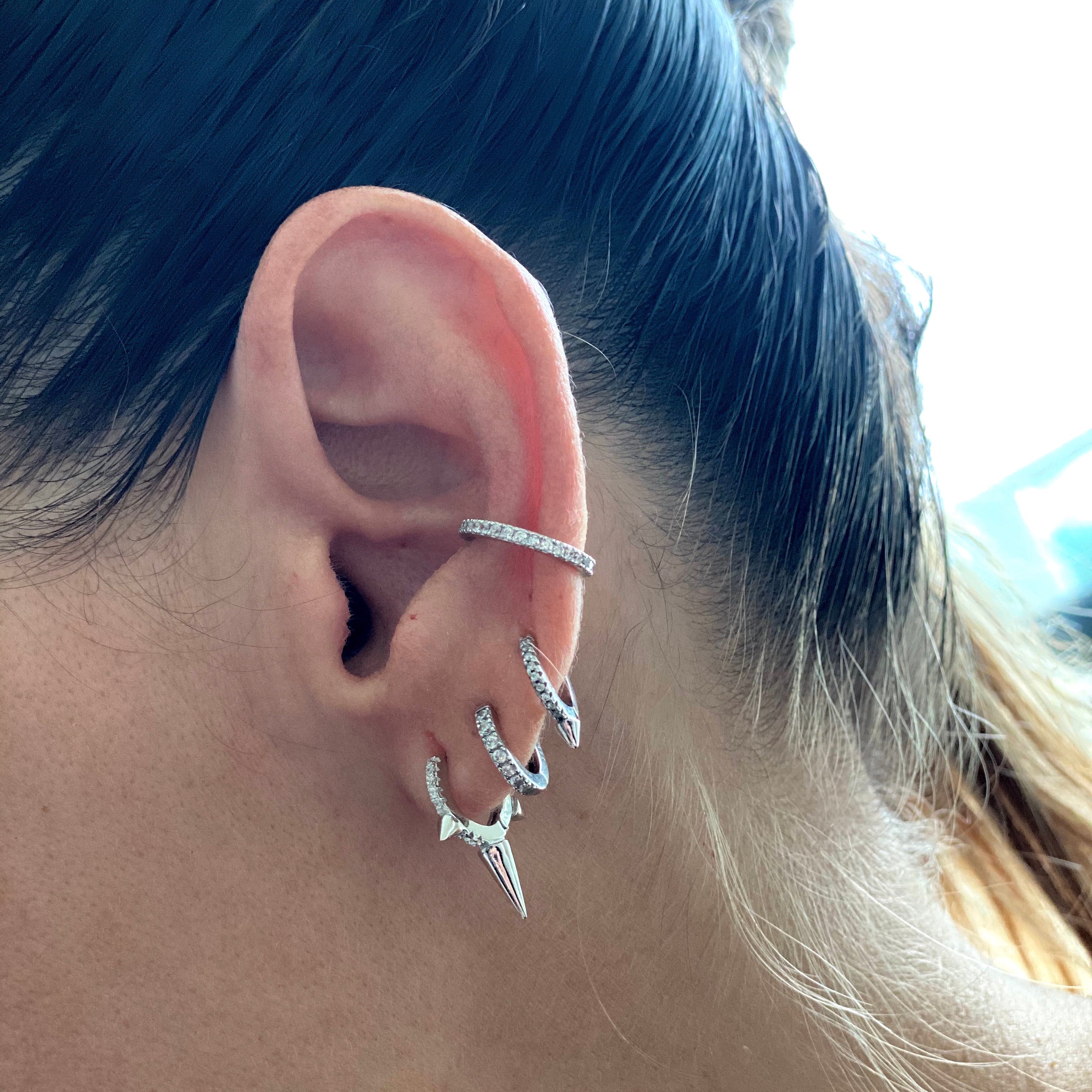 EAR PARTY SET - 3 & 2 HOLES in Silver which comes with 5 earrings. 4 hoop earrings and one ear cuff. On this photo are three hoop earrings one with small spike and the other has a longer spike to it. the other one is just plain hoop. In the middle of the ear is the clear cuff earring in silver. ||| SILVER
