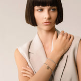 Model wearing the Tennis and the Box Bracelet Set, a two-piece silver bracelet set featuring a diamond-like tennis bracelet and a box chain bracelet with a gold north star charm accented with diamond-like stones.