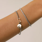 Model wearing the Tennis and the Box Bracelet Set, a two-piece silver bracelet set featuring a diamond-like tennis bracelet and a box chain bracelet with a gold north star charm accented with diamond-like stones.