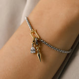 Model wearing the Can Opener Chain Bracelet featuring a silver link chain with bold gold link spike charm and a sparkling DROP LINK pendant. 