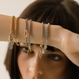 Model wearing layered can opener bracelets including the Can Opener Chain Bracelet featuring a silver link chain with bold gold link spike charm and a sparkling DROP LINK pendant. 
