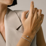 Model wearing the Solitaire Adjustable Bracelet, a silver adjustable bracelet with a delicate chain and a single diamond-like stone cluster.