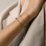 Model wearing the Solitaire Adjustable Bracelet, a silver adjustable bracelet with a delicate chain and a single diamond-like stone cluster.