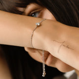 Model wearing the Solitaire Adjustable Bracelet, a silver adjustable bracelet with a delicate chain and a single diamond-like stone cluster.