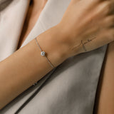 Model wearing the Solitaire Adjustable Bracelet, a silver adjustable bracelet with a delicate chain and a single diamond-like stone cluster.