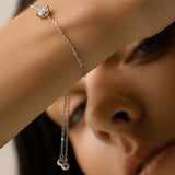 Model wearing the Solitaire Adjustable Bracelet, a silver adjustable bracelet with a delicate chain and a single diamond-like stone cluster.
