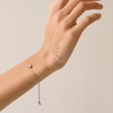 Model wearing the Solitaire Adjustable Bracelet, a silver adjustable bracelet with a delicate chain and a single diamond-like stone cluster.