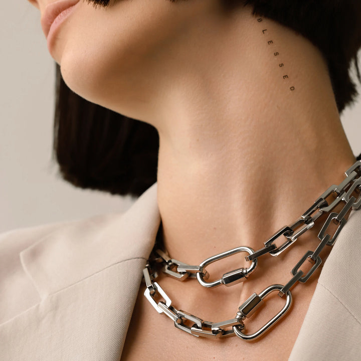 Model  wearing two Carabiner Square Puerto Necklaces, which is a silver chain necklace featuring a unique silver carabiner clasp. ||| SILVER