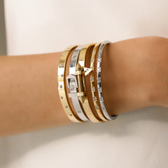 Model wearing  the Triangle Stack, a five-piece bangle set featuring gold and silver bangles with cubic zirconia accents and a triangle clasp detail.