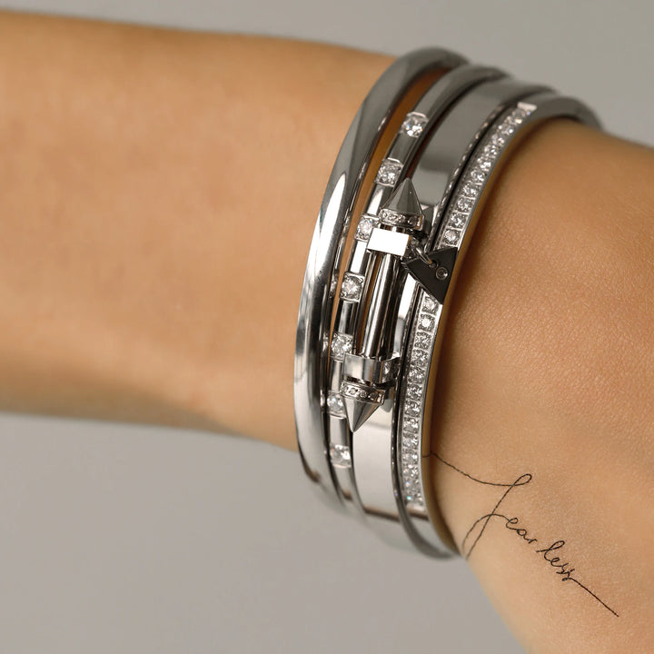 Model wearing The ARROW STACK, a stunning silver bangle set featuring 4 bracelet stack with intricate arrowhead details and sparkling diamonds. 