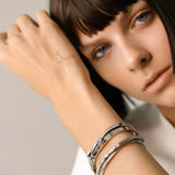 Model wearing The ARROW STACK, a stunning silver bangle set featuring 4 bracelet stack with intricate arrowhead details and sparkling diamonds. 
