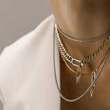 Model wearing the Triangle Necklace Set, a three-piece necklace set with gold and silver chains, including a cuban link, a box chain, and a tennis chain with triangle spike charms.