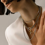 Model wearing the Triangle Necklace Set, a three-piece necklace set with gold and silver chains, including a cuban link, a box chain, and a tennis chain with triangle spike charms.