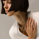 Model wearing the Triangle Necklace Set, a three-piece necklace set with gold and silver chains, including a cuban link, a box chain, and a tennis chain with triangle spike charms.