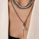 Model wearing the Needle and the Tennis Necklace Set, a three-piece silver necklace set featuring two chains, a diamond-like tennis necklace, and a dangling spike charm.