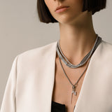Model wearing the Needle and the Tennis Necklace Set, a three-piece silver necklace set featuring two chains, a diamond-like tennis necklace, and a dangling spike charm.