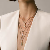 Model wearing the Tag Needle Necklace Set, a three-piece silver necklace set featuring three chains with two diamond-like encrusted dog tag charms and a spike charm.