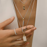 Model wearing the Tag Needle Necklace Set, a three-piece silver necklace set featuring three chains with two diamond-like encrusted dog tag charms and a spike charm.