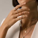 Model wearing the Tag Needle Necklace Set, a three-piece silver necklace set featuring three chains with two diamond-like encrusted dog tag charms and a spike charm.