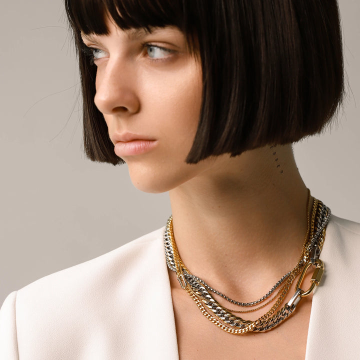 Model wearing the Carabiner Necklace Set, a three-piece gold and silver necklace set featuring Cuban link chains and a carabiner clasp.
