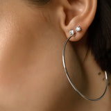 The Solitaire Hoop, a pair of silver hoop earrings with a diamond-like stone stud.