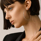Model wearing the Solitaire Hoop, a pair of silver hoop earrings with a diamond-like stone stud.