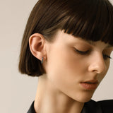 Model wearing one Eternity Emerald Hoops, a silver hoop featuring emerald accents.
