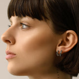 Model wearing the Eternity Emerald Hoops, a pair of silver hoops featuring emerald accents.