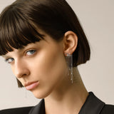 Model wearing the Rain Drop Earrings, a pair of silver earrings featuring cascading chains with diamond-like accents.
