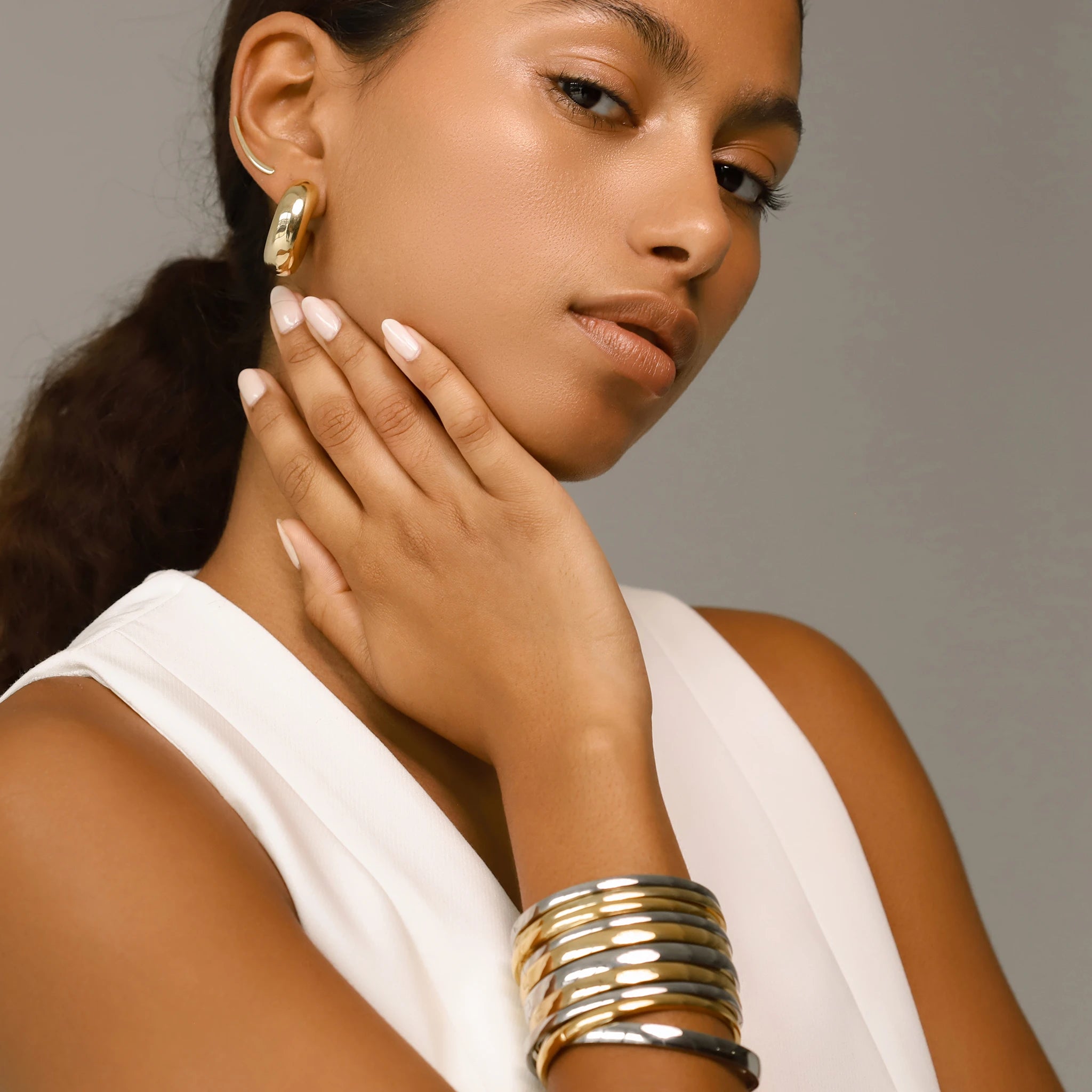 The Plain Thin Set, which is a four-piece bracelet stack, features a mix of polished gold and silver bands, offering a bold yet minimalist aesthetic that complements any outfit for a chic and effortless statement.