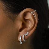 The Prong Hoops, which are a pair of elegant silver hoop earrings, feature sparkling prong-set crystals designed to catch the light beautifully. These versatile earrings add a touch of sophistication to any look and can be worn alone or styled with other silver pieces for a layered effect. ||| SILVER