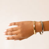 The Doble Plain Set which is a two-piece bracelet stack featuring a polished gold-toned bangle and a sleek silver-toned bangle, designed for a sophisticated and modern mixed-metal look that effortlessly complements any outfit. 