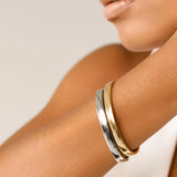 The Doble Plain Set which is a two-piece bracelet stack featuring a polished gold-toned bangle and a sleek silver-toned bangle, designed for a sophisticated and modern mixed-metal look that effortlessly complements any outfit.