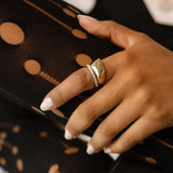 The Deformed Rectangle Ring, which is a single-piece gold ring, features a bold and contemporary abstract rectangular design with a polished finish. Paired elegantly with silver stackable bands adorned with sparkling stones, it creates a striking mixed-metal look perfect for modern, chic styling. A versatile accessory for both casual and formal outfits.