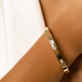 Model wearing the Arrow Bangle, a gold bangle with diamond-like accents. ||| GOLD