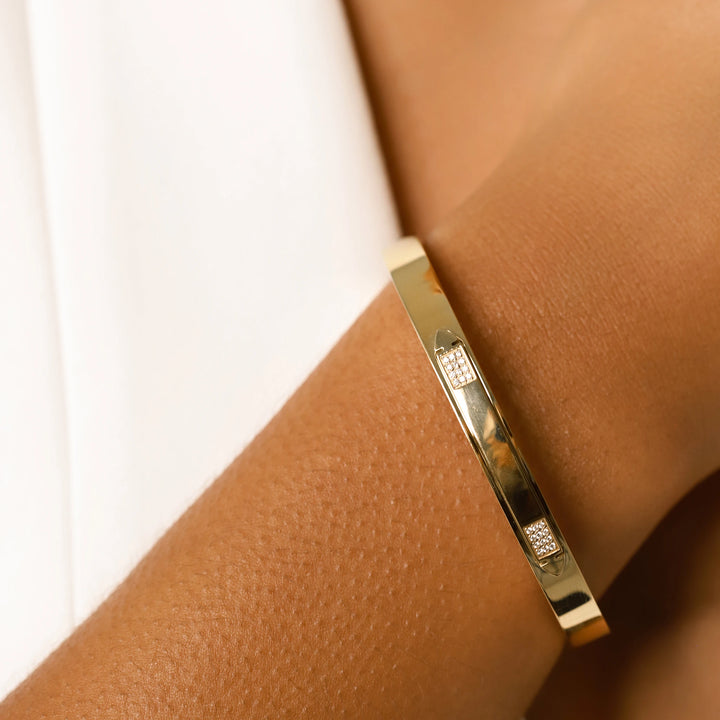 Model wearing the Arrow Bangle, a gold bangle with diamond-like accents. ||| GOLD