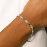 Model wearing the Spiga Tennis Bracelet, a silver bracelet with a wheat link chain design and diamond-like stones.