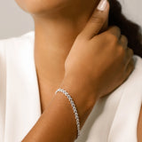 Model wearing the Spiga Tennis Bracelet, a silver bracelet with a wheat link chain design and diamond-like stones.