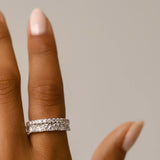 Model wearing the Triangle Ring, a silver ring featuring a row of triangle-shaped cubic zirconia stones and the all around eternity band.